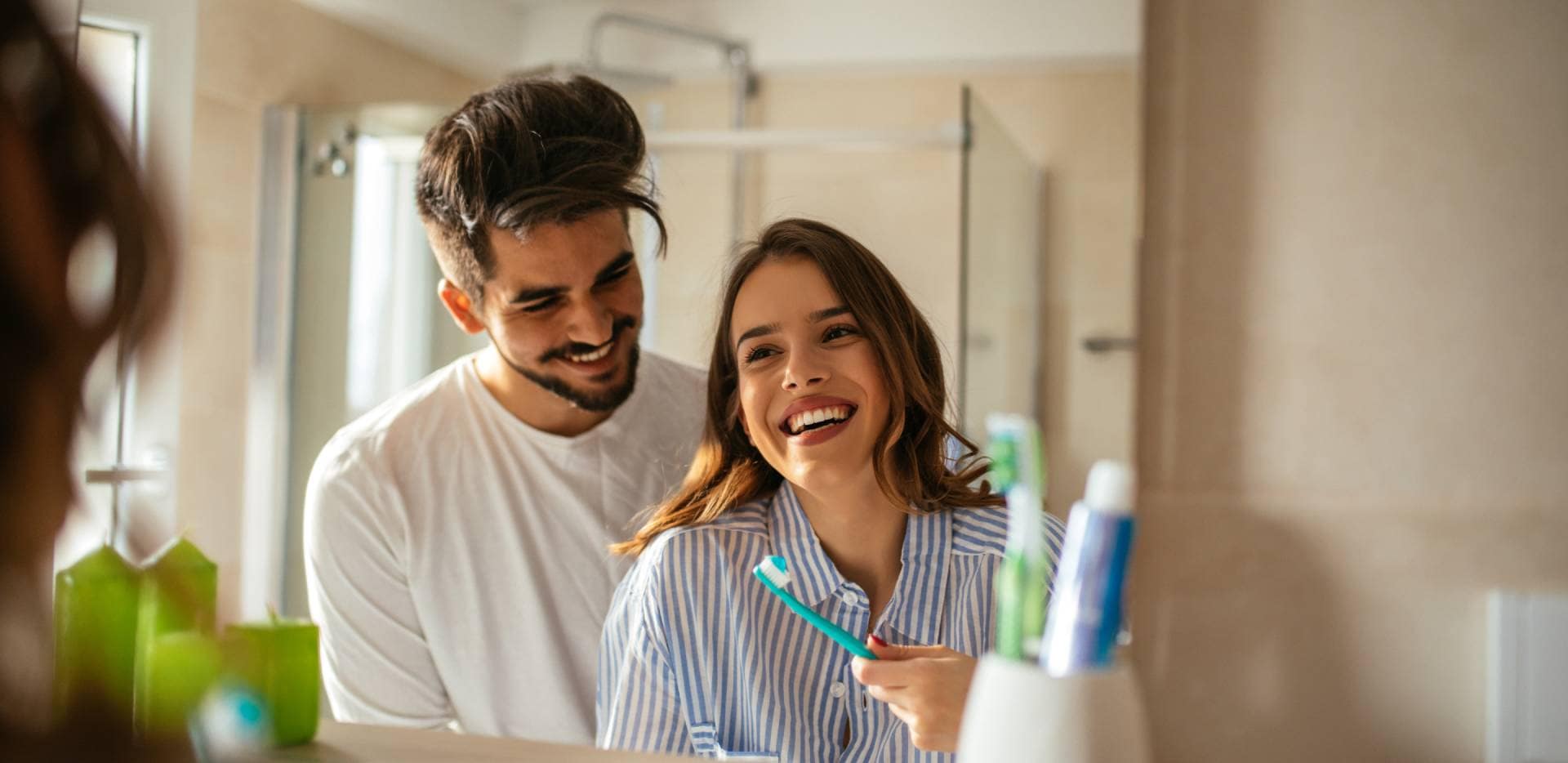 Couple souriant devant un miroir en se brossant les dents